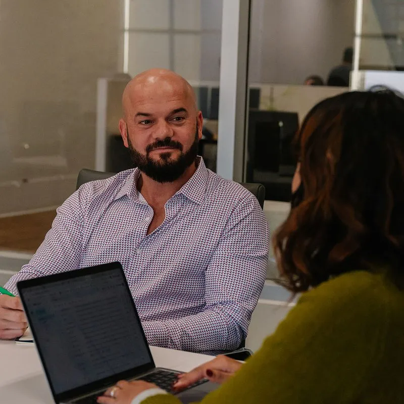 A woman and man in a meeting seated at a conference table.